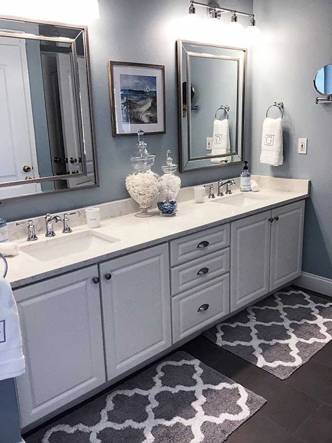 Photo of a mid-sized beach style master bathroom in Orlando with raised-panel cabinets, white cabinets, a corner tub, an alcove shower, multi-coloured tile, porcelain tile, blue walls, porcelain floors, an undermount sink, engineered quartz benchtops, grey floor, a hinged shower door, multi-coloured benchtops, a double vanity and a built-in vanity.