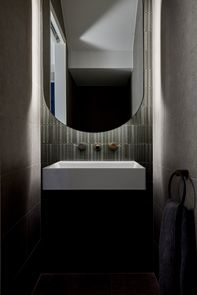 Photo of a small contemporary powder room in Melbourne with a wall-mount toilet, green tile, grey walls, porcelain floors, a wall-mount sink, grey floor and a floating vanity.