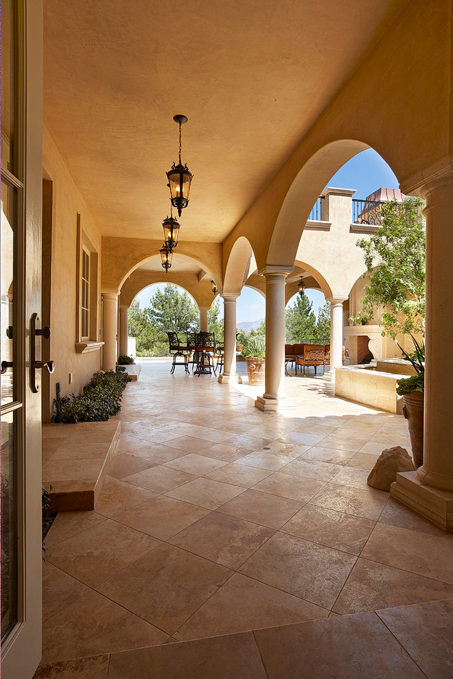 This is an example of a large mediterranean courtyard patio in Orange County with tile and a roof extension.