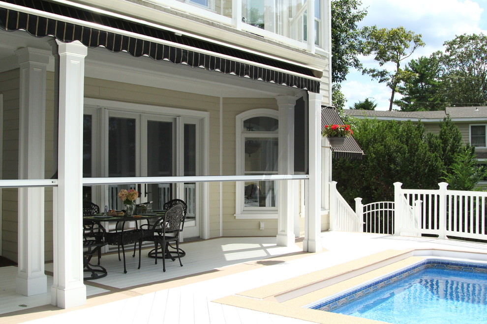 Large traditional backyard screened-in verandah in New York with decking and an awning.