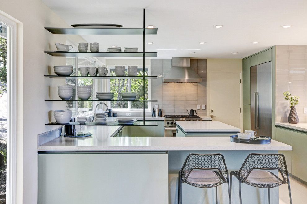 Photo of a medium sized modern u-shaped kitchen/diner in San Francisco with a submerged sink, flat-panel cabinets, green cabinets, engineered stone countertops, grey splashback, ceramic splashback, stainless steel appliances, an island and white worktops.