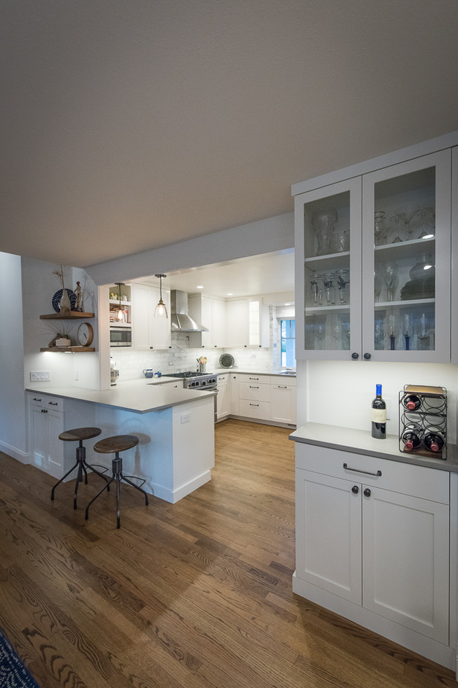 Kitchen - transitional u-shaped medium tone wood floor kitchen idea with shaker cabinets, white cabinets, gray backsplash, stainless steel appliances and an undermount sink