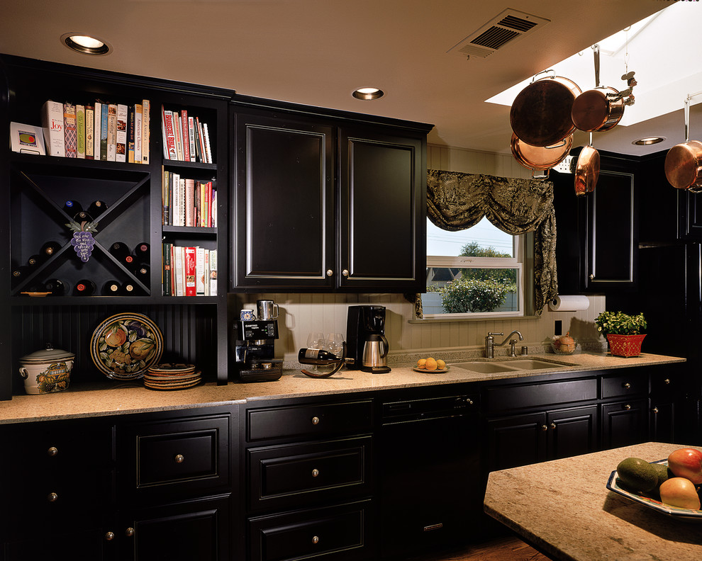 Photo of a large traditional galley kitchen in Orange County with with island, a double-bowl sink, raised-panel cabinets, black cabinets, marble benchtops, beige splashback, ceramic splashback and black appliances.
