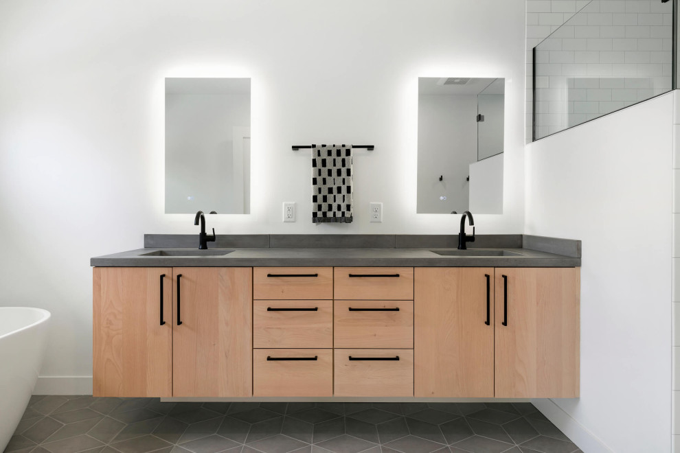 This is an example of a mid-sized modern master bathroom in Minneapolis with light wood cabinets, a freestanding tub, white walls, brown floor, grey benchtops, a double vanity and a floating vanity.