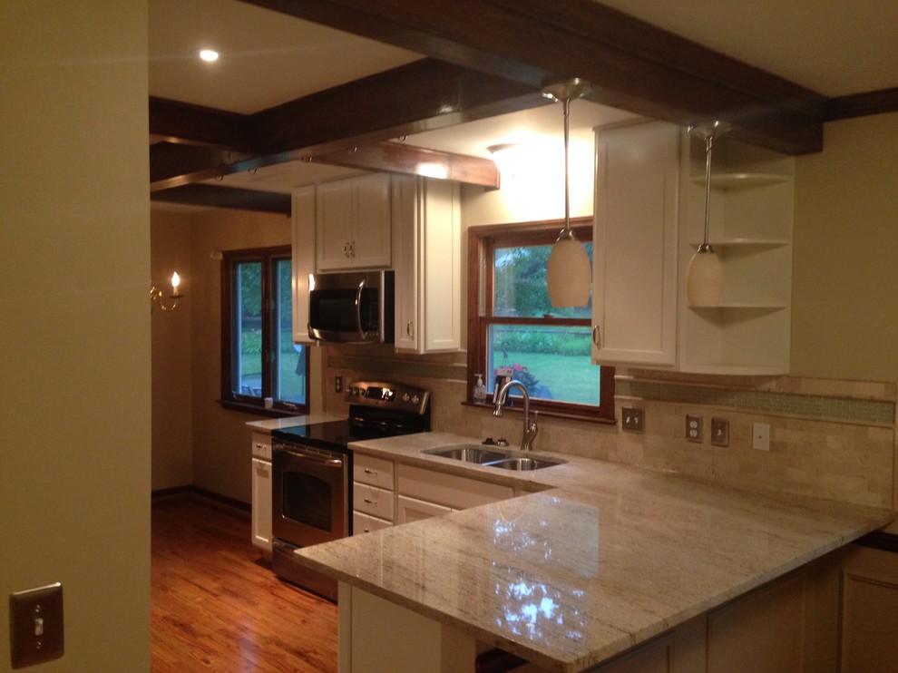 Inspiration for a mid-sized transitional l-shaped medium tone wood floor kitchen remodel in Cincinnati with a double-bowl sink, raised-panel cabinets, white cabinets, granite countertops, beige backsplash, ceramic backsplash and stainless steel appliances