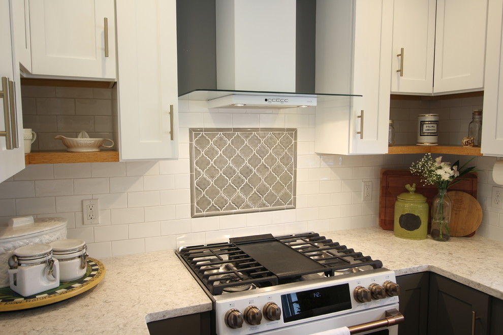 Example of a mid-sized transitional u-shaped medium tone wood floor and brown floor enclosed kitchen design with a farmhouse sink, shaker cabinets, white cabinets, quartz countertops, white backsplash, subway tile backsplash, white appliances, no island and beige countertops