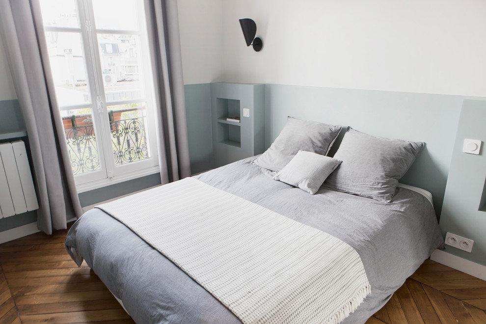 This is an example of a small scandinavian master bedroom in Paris with green walls and light hardwood floors.