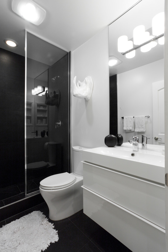 This is an example of a contemporary bathroom in Sacramento with a wall-mount sink, flat-panel cabinets, white cabinets, an alcove shower, a two-piece toilet, black tile and black floor.