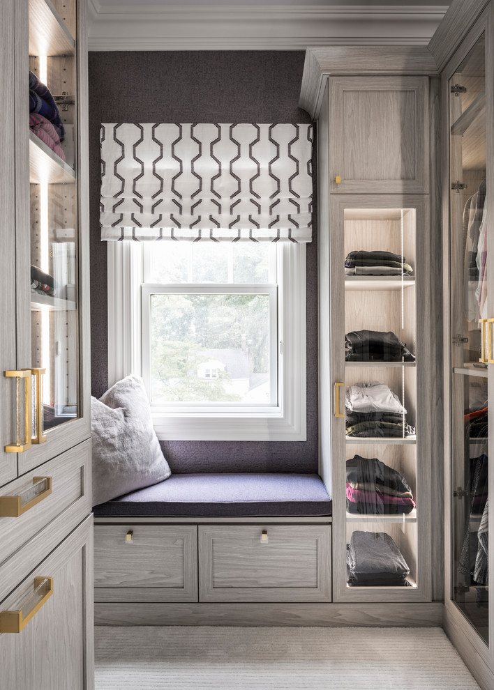 Design ideas for a transitional women's walk-in wardrobe in New York with glass-front cabinets, carpet and grey floor.
