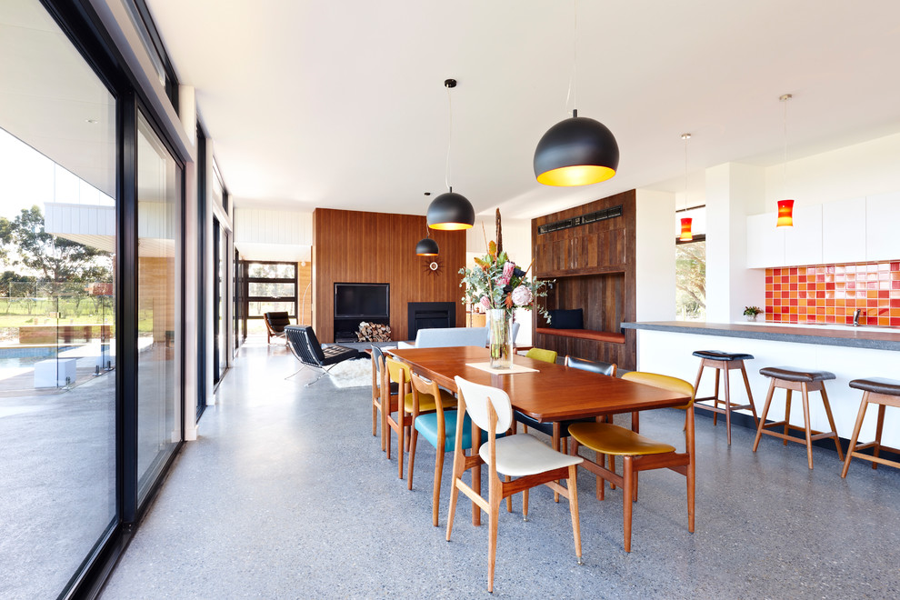 Contemporary open plan dining in Melbourne with white walls, a standard fireplace, a wood fireplace surround and grey floor.