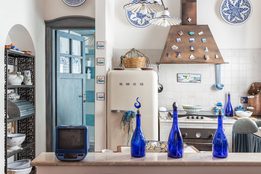 Inspiration for a small beach style l-shaped eat-in kitchen in Rome with tile benchtops, white splashback, white appliances, white benchtop, a double-bowl sink, open cabinets, no island and brown floor.