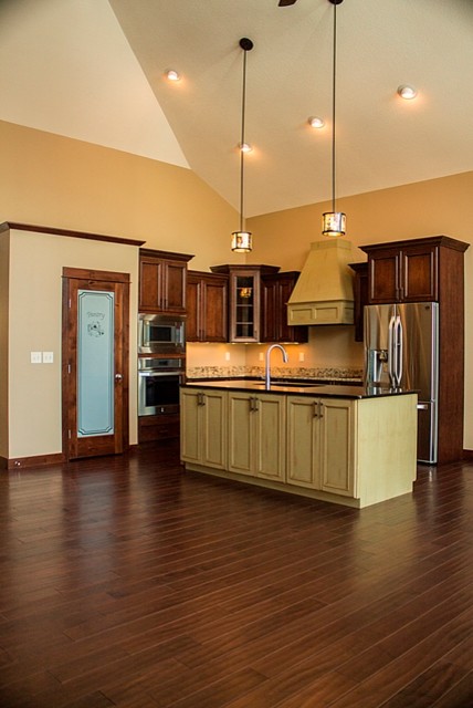 Mountain style kitchen photo with glass-front cabinets, granite countertops, stainless steel appliances, black walls and engineered wood floors