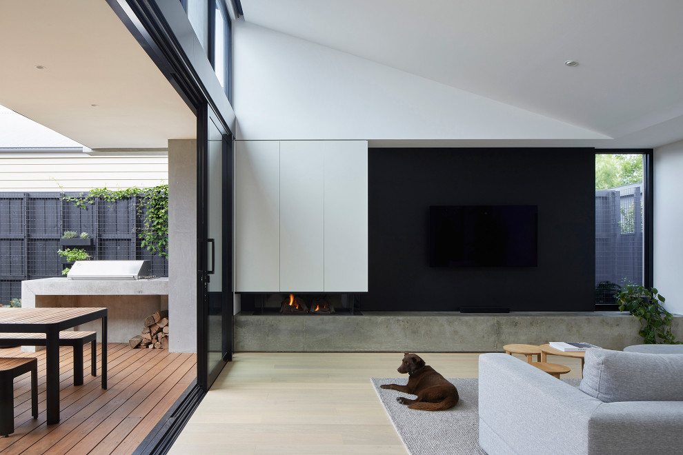 Идея дизайна: открытая гостиная комната в современном стиле с черными стенами, светлым паркетным полом, стандартным камином, фасадом камина из бетона, бежевым полом и сводчатым потолком