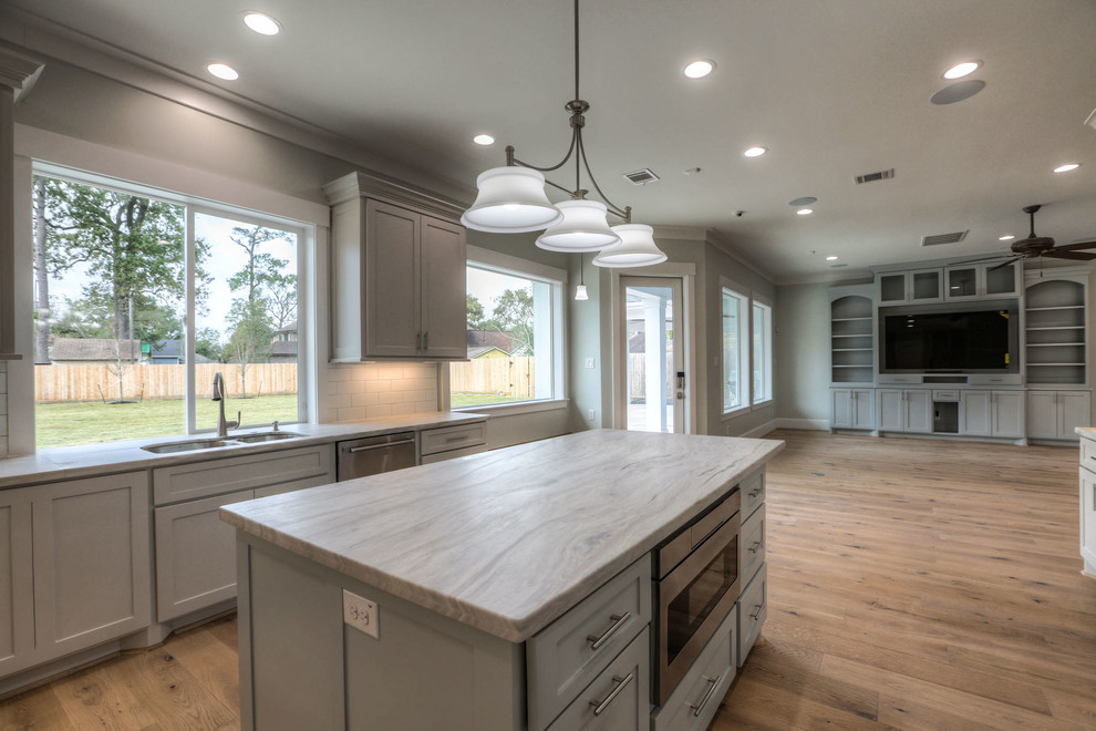Mid-sized transitional u-shaped light wood floor and beige floor enclosed kitchen photo in Houston with shaker cabinets, gray cabinets, white backsplash, stainless steel appliances, an island, a double-bowl sink, quartz countertops and subway tile backsplash