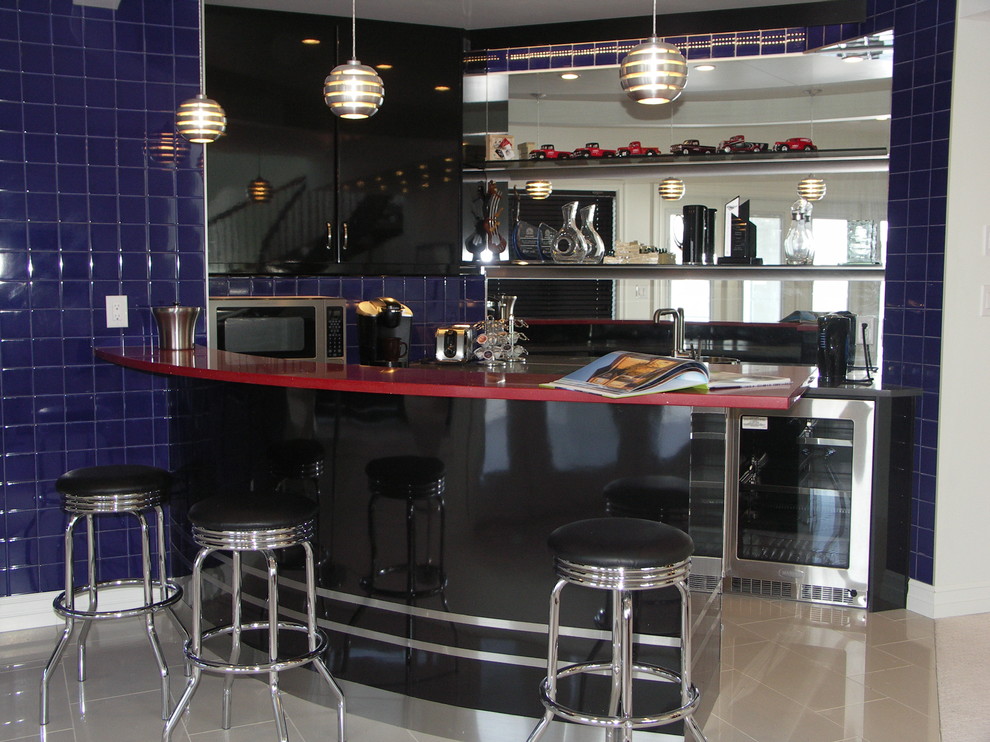 Design ideas for a mid-sized transitional u-shaped seated home bar in Edmonton with a drop-in sink, flat-panel cabinets, black cabinets, solid surface benchtops, mirror splashback, porcelain floors, blue splashback, beige floor and red benchtop.