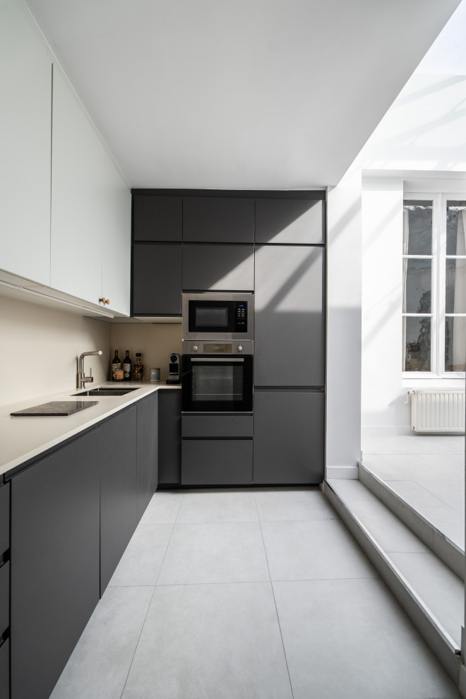 Bild på ett mellanstort funkis vit vitt kök, med en undermonterad diskho, luckor med infälld panel, grå skåp, beige stänkskydd, integrerade vitvaror och grått golv