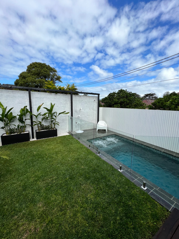 Idée de décoration pour un piscine avec aménagement paysager arrière minimaliste de taille moyenne et rectangle avec des pavés en pierre naturelle.