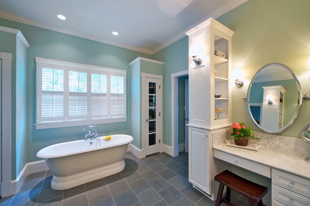 Photo of a mid-sized traditional master wet room bathroom in Orange County with recessed-panel cabinets, white cabinets, a freestanding tub, white tile, stone slab, blue walls, slate floors, marble benchtops, an undermount sink and a hinged shower door.