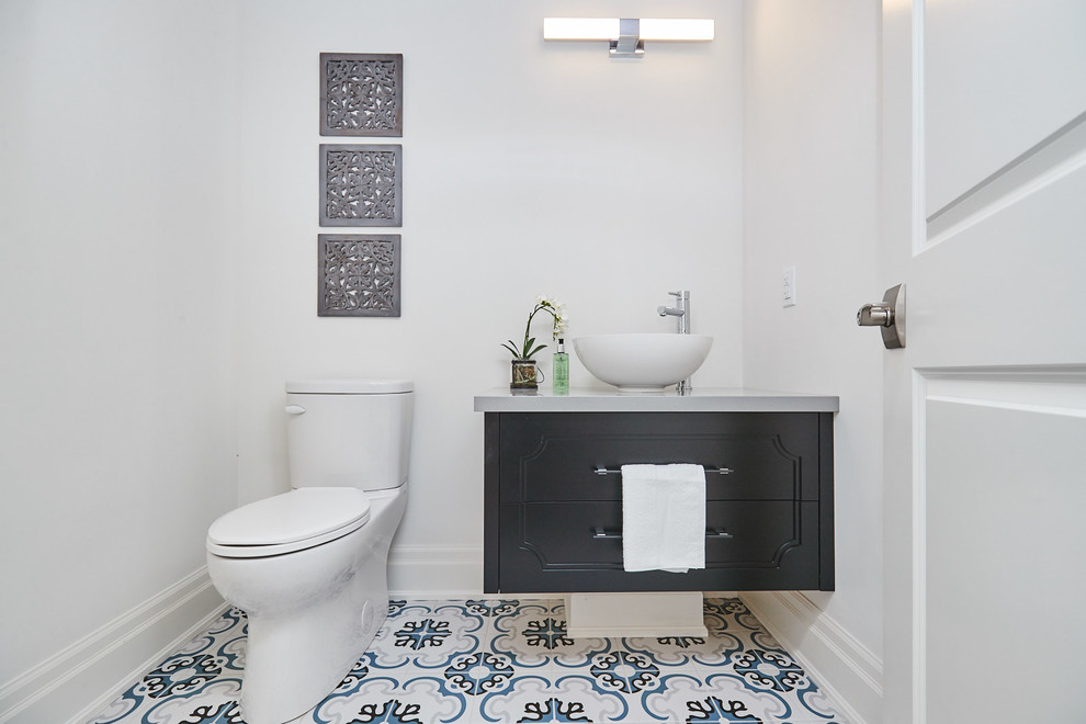 Photo of a mid-sized transitional powder room in Other with beaded inset cabinets, black cabinets, a two-piece toilet, grey walls, porcelain floors, a vessel sink, quartzite benchtops, blue floor and grey benchtops.