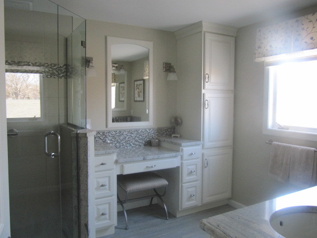 Photo of a mid-sized beach style master bathroom in Providence with beige walls, raised-panel cabinets, white cabinets, a corner shower, porcelain floors, an undermount sink, marble benchtops, beige floor and a hinged shower door.