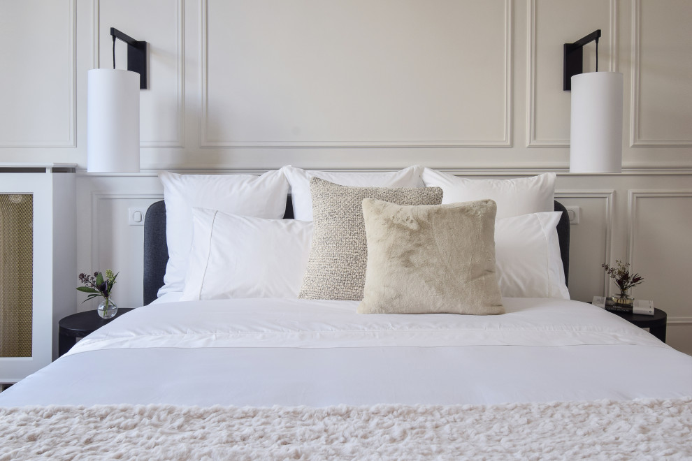 Ejemplo de dormitorio principal y beige y blanco clásico de tamaño medio sin chimenea con paredes blancas, suelo de madera clara, suelo beige y boiserie
