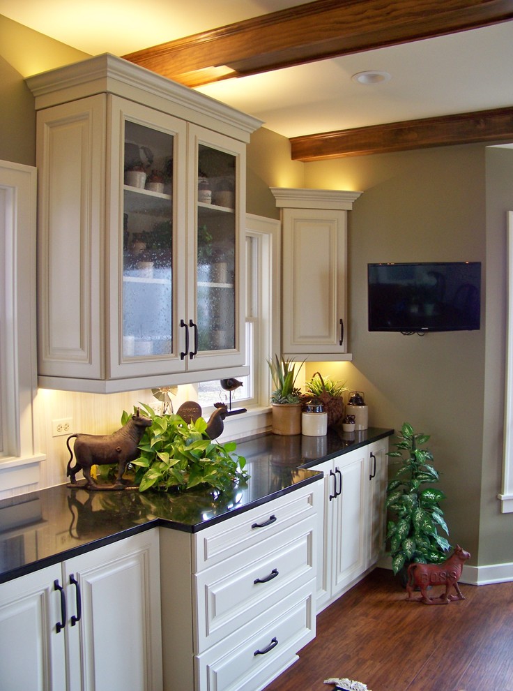 Example of a mid-sized transitional l-shaped medium tone wood floor and brown floor eat-in kitchen design in Chicago with an undermount sink, raised-panel cabinets, white cabinets, solid surface countertops, white backsplash, wood backsplash, white appliances and no island