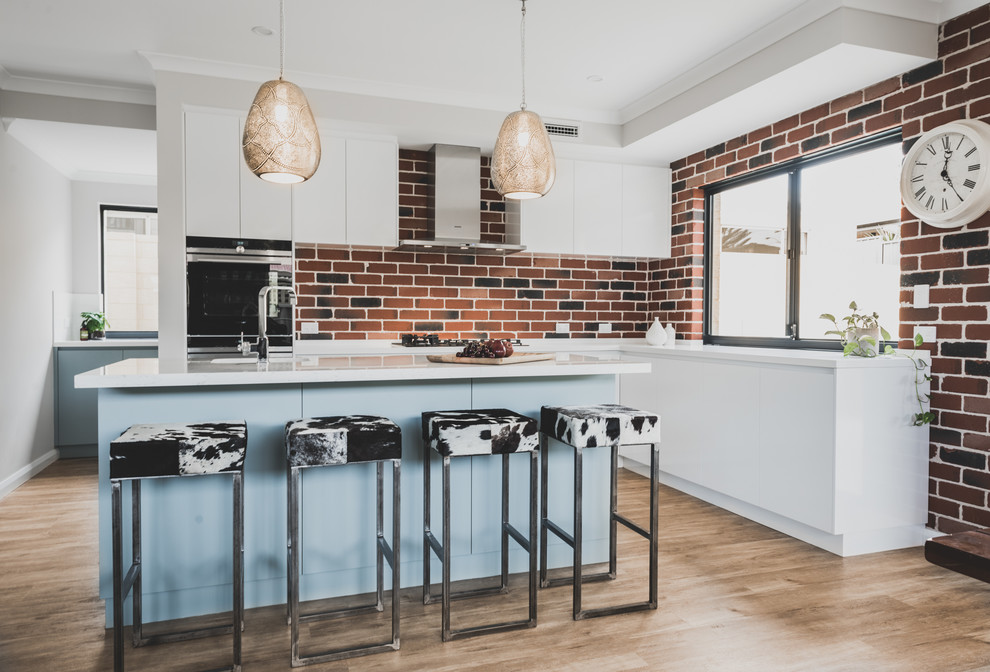 Design ideas for a contemporary l-shaped kitchen in Perth with brick splashback, with island, white benchtop, flat-panel cabinets, white cabinets, red splashback and brown floor.