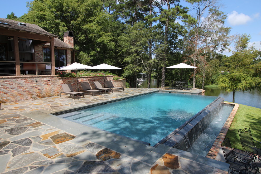 Pool - mid-sized transitional backyard stone and rectangular infinity pool idea in New Orleans