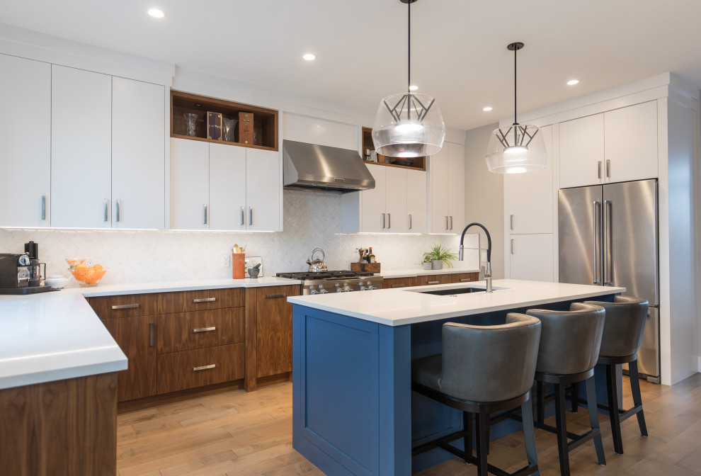 Eat-in kitchen - large transitional l-shaped light wood floor and brown floor eat-in kitchen idea in Calgary with an undermount sink, flat-panel cabinets, white backsplash, stainless steel appliances, an island and white countertops