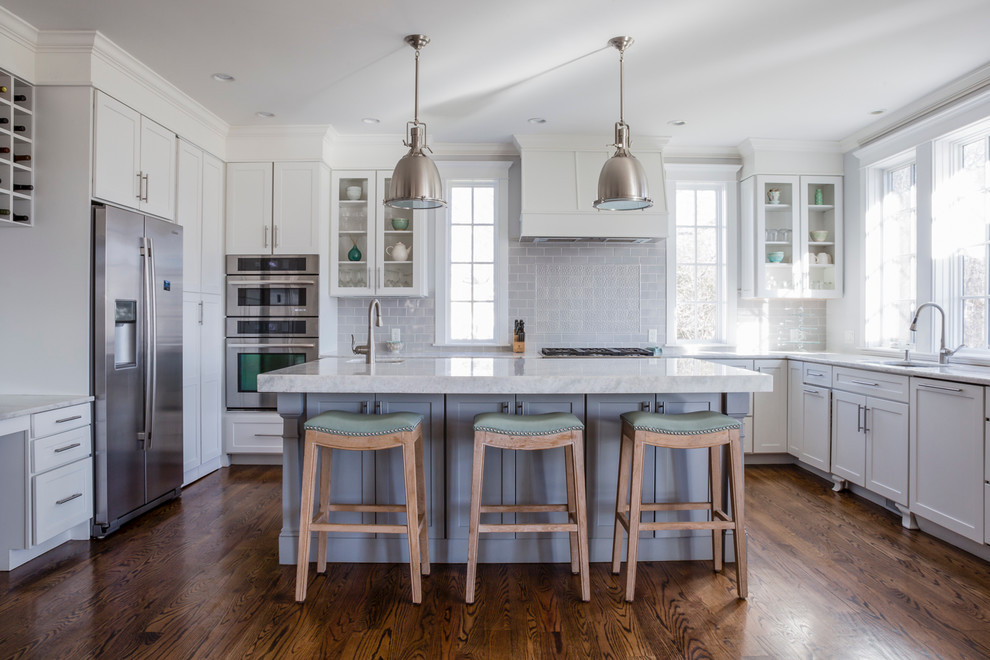 Example of a mid-sized transitional u-shaped dark wood floor open concept kitchen design with shaker cabinets, white cabinets, quartzite countertops, gray backsplash, ceramic backsplash, stainless steel appliances, an island and white countertops
