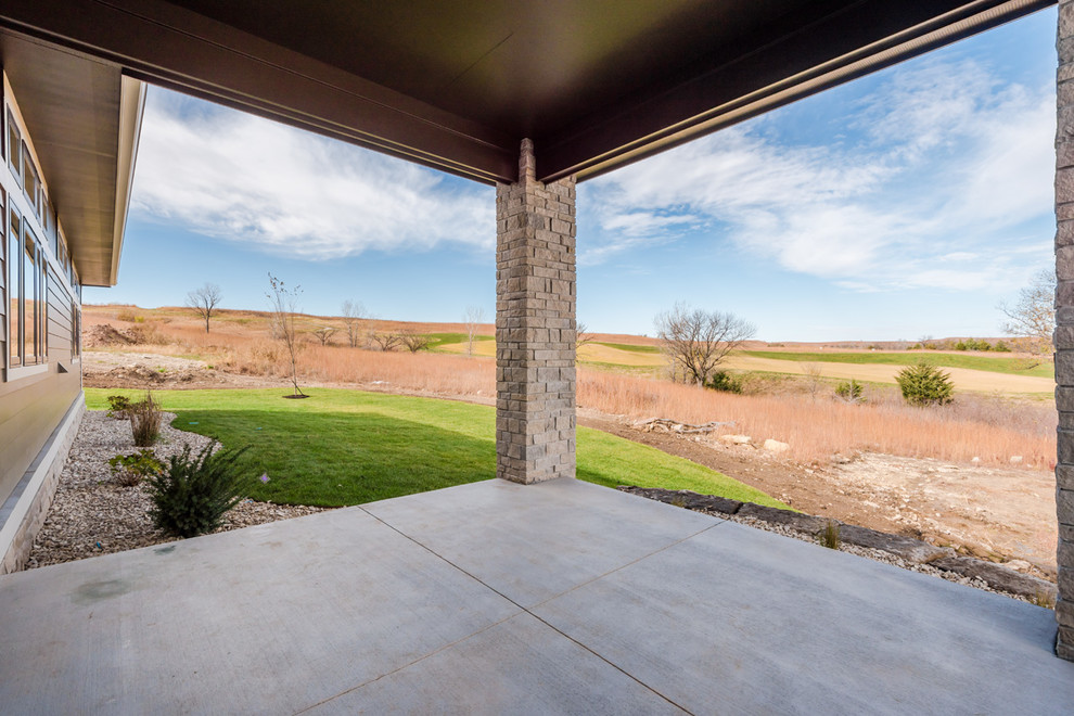 Example of a mid-sized transitional side yard concrete home design design with a roof extension