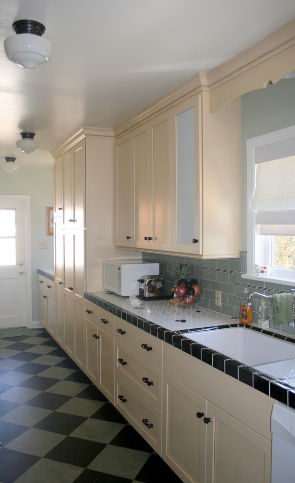 Photo of a traditional galley eat-in kitchen in Los Angeles with an undermount sink, shaker cabinets, beige cabinets, tile benchtops, green splashback, subway tile splashback and white appliances.