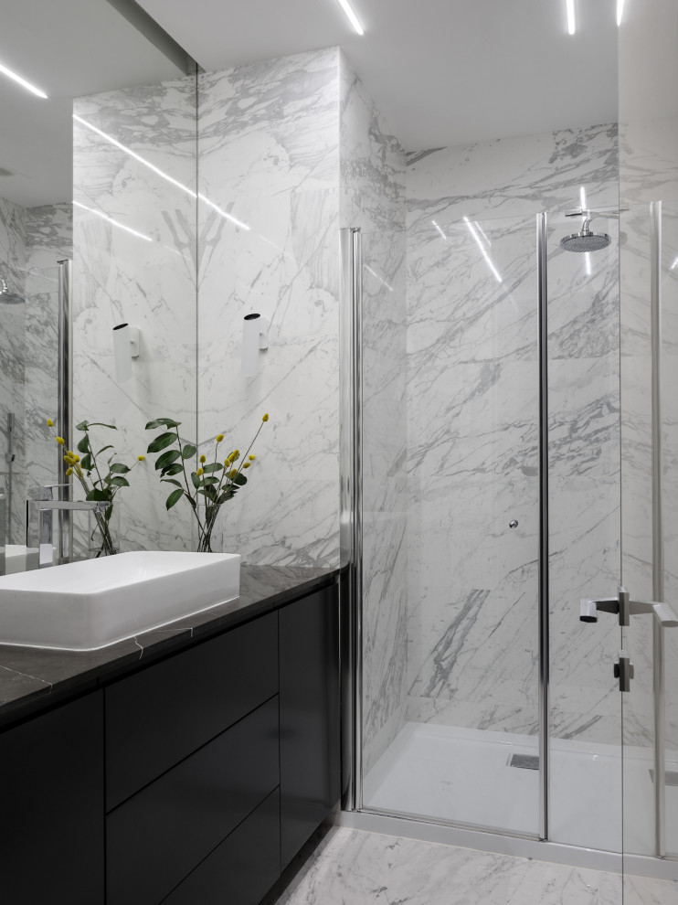 Photo of a small contemporary 3/4 bathroom in Moscow with flat-panel cabinets, grey cabinets, an alcove shower, a wall-mount toilet, white tile, porcelain tile, white walls, a drop-in sink, marble benchtops, a hinged shower door, black benchtops, a single vanity and a freestanding vanity.