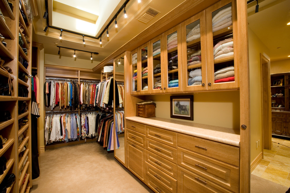 Inspiration for an expansive arts and crafts gender-neutral walk-in wardrobe in Las Vegas with medium wood cabinets, carpet, beige floor and vaulted.