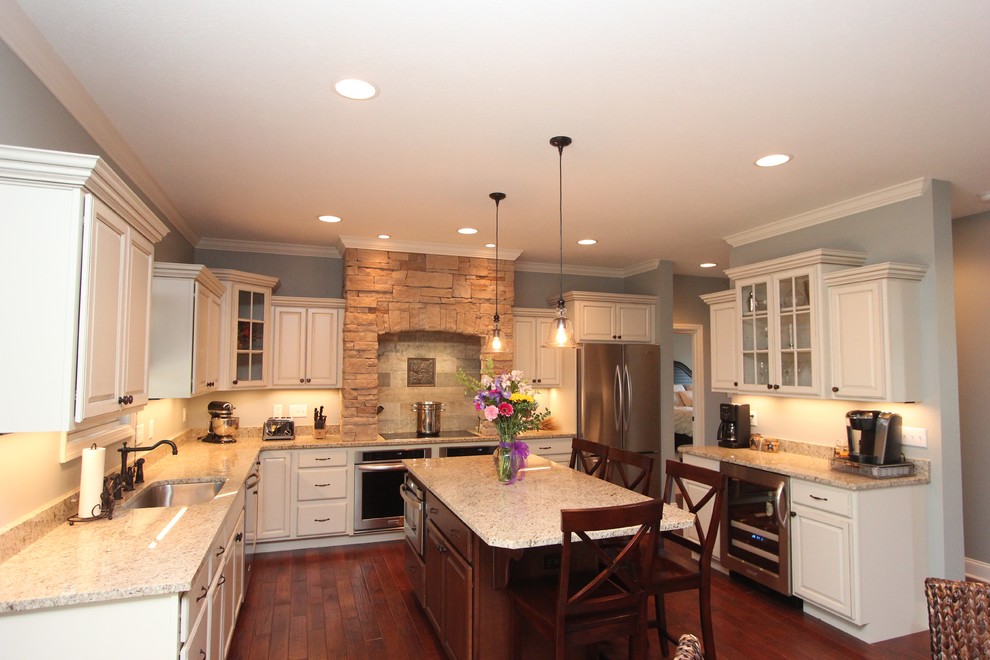 Large transitional u-shaped dark wood floor eat-in kitchen photo with an undermount sink, raised-panel cabinets, white cabinets, granite countertops, stainless steel appliances and an island