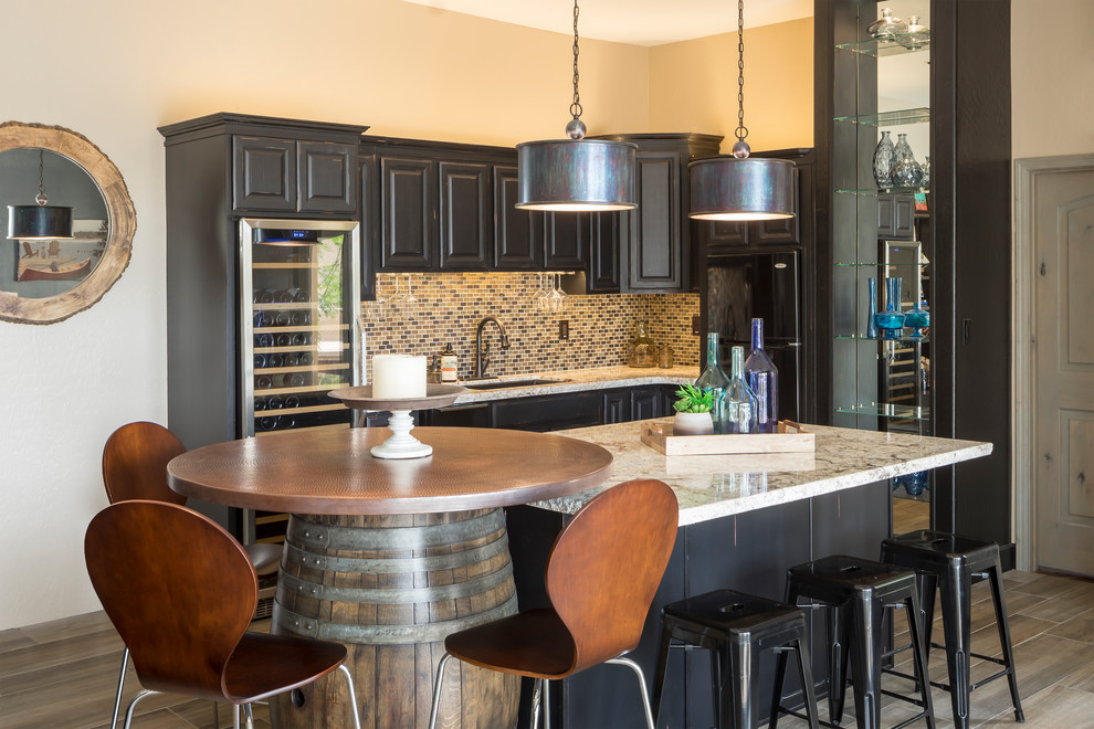 Mid-sized eclectic l-shaped home bar in Phoenix with an undermount sink, raised-panel cabinets, distressed cabinets, granite benchtops, porcelain floors and grey floor.