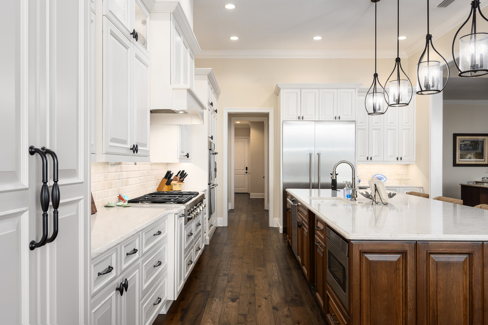 Inspiration for a large transitional l-shaped open plan kitchen in Jacksonville with an undermount sink, raised-panel cabinets, white cabinets, quartz benchtops, beige splashback, marble splashback, stainless steel appliances, dark hardwood floors, with island, brown floor and beige benchtop.