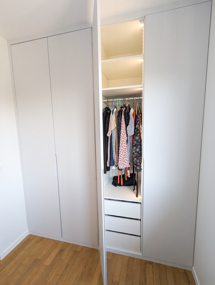 Photo of a mid-sized contemporary gender-neutral built-in wardrobe in Other with medium hardwood floors.