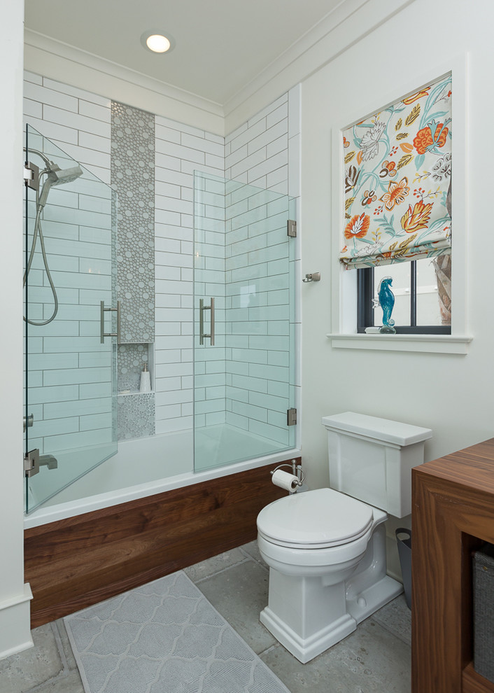 Photo of a beach style 3/4 bathroom in Miami with an alcove tub, a shower/bathtub combo, a two-piece toilet, subway tile, white walls, concrete floors, wood benchtops, dark wood cabinets, a vessel sink and a hinged shower door.