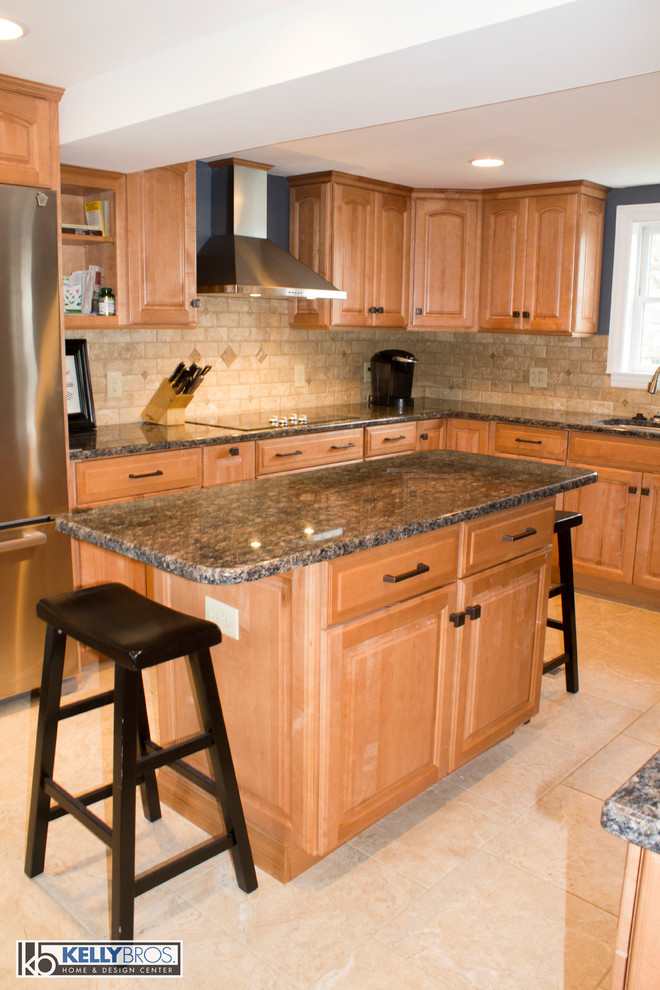 Photo of a large transitional l-shaped eat-in kitchen in Cincinnati with an undermount sink, raised-panel cabinets, light wood cabinets, granite benchtops, beige splashback, stone tile splashback, stainless steel appliances, ceramic floors and with island.