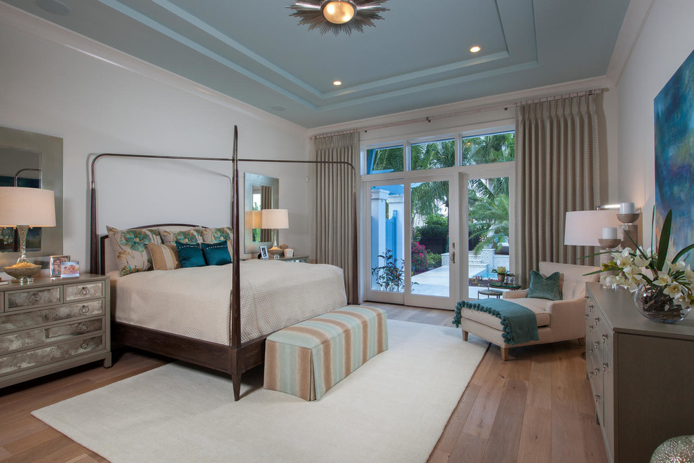 Photo of a tropical master bedroom in Miami with light hardwood floors.