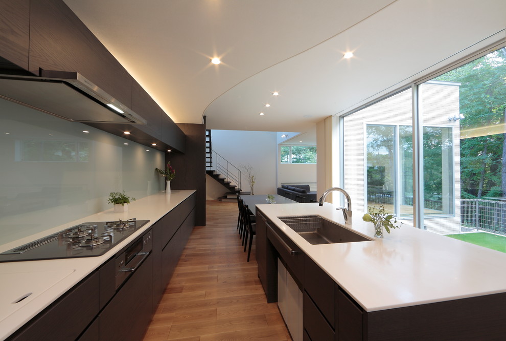 Design ideas for a contemporary galley open plan kitchen in Sapporo with a single-bowl sink, flat-panel cabinets, dark wood cabinets, white splashback, medium hardwood floors and with island.