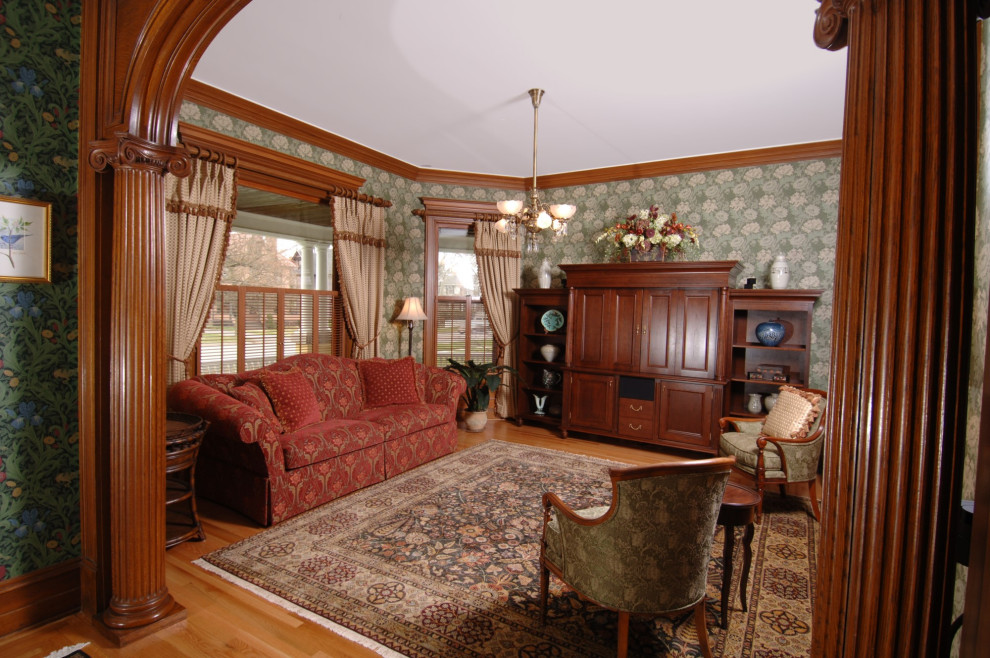 Photo of a mid-sized traditional formal enclosed living room in New York with green walls, light hardwood floors, no fireplace and a concealed tv.