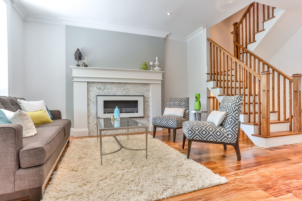 This is an example of a mid-sized contemporary formal open concept living room in Toronto with grey walls, medium hardwood floors, a standard fireplace, a stone fireplace surround and no tv.