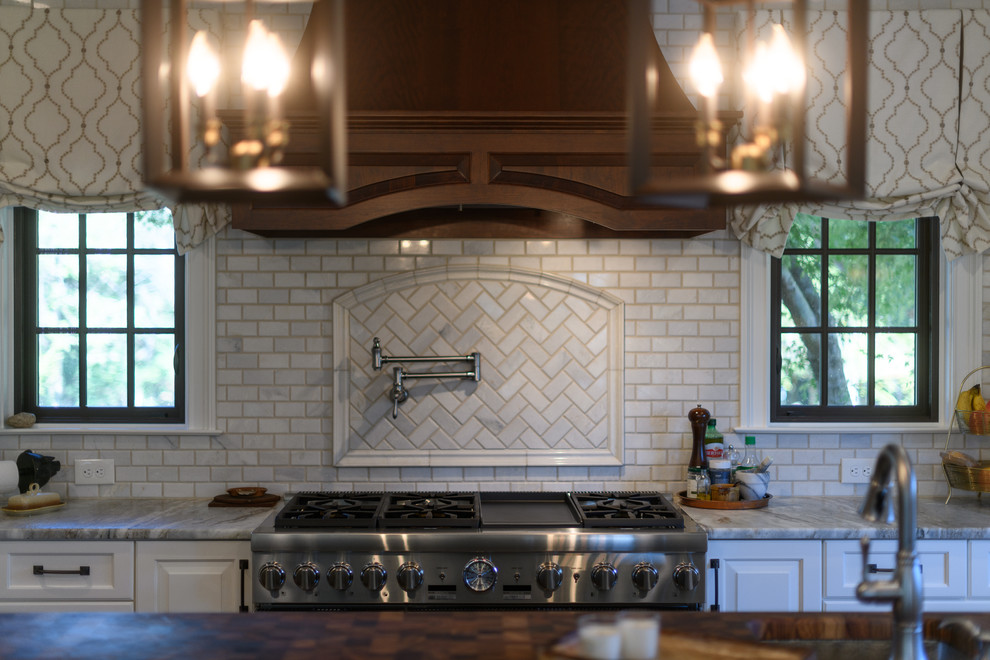 Inspiration for a large transitional l-shaped dark wood floor and brown floor kitchen remodel with an undermount sink, raised-panel cabinets, white cabinets, quartzite countertops, white backsplash, marble backsplash, stainless steel appliances and an island