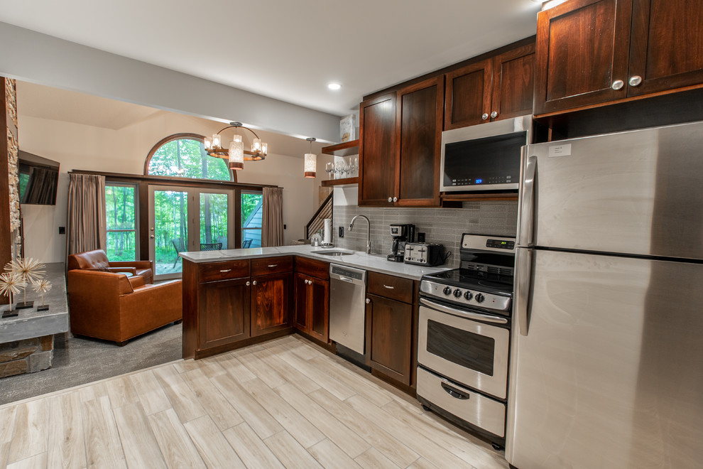 Open concept kitchen - mid-sized transitional l-shaped ceramic tile and beige floor open concept kitchen idea with an undermount sink, shaker cabinets, dark wood cabinets, quartz countertops, gray backsplash, ceramic backsplash, stainless steel appliances, no island and white countertops