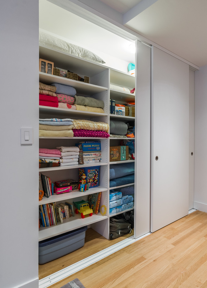 Photo of a large contemporary kids' bedroom for boys in New York with white walls and light hardwood floors.