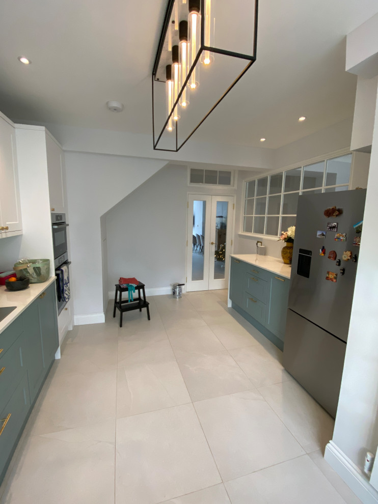 This is an example of a large contemporary galley kitchen/diner in London with quartz worktops, white splashback, porcelain flooring and no island.