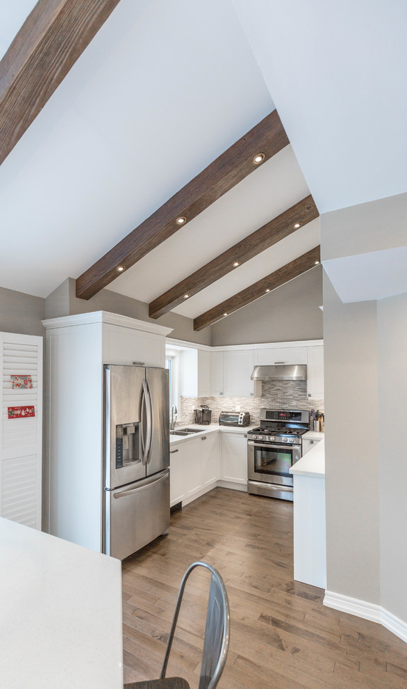 Inspiration for a mid-sized transitional u-shaped medium tone wood floor and brown floor open concept kitchen remodel in Toronto with a double-bowl sink, recessed-panel cabinets, white cabinets, quartz countertops, gray backsplash, marble backsplash, stainless steel appliances, no island and white countertops