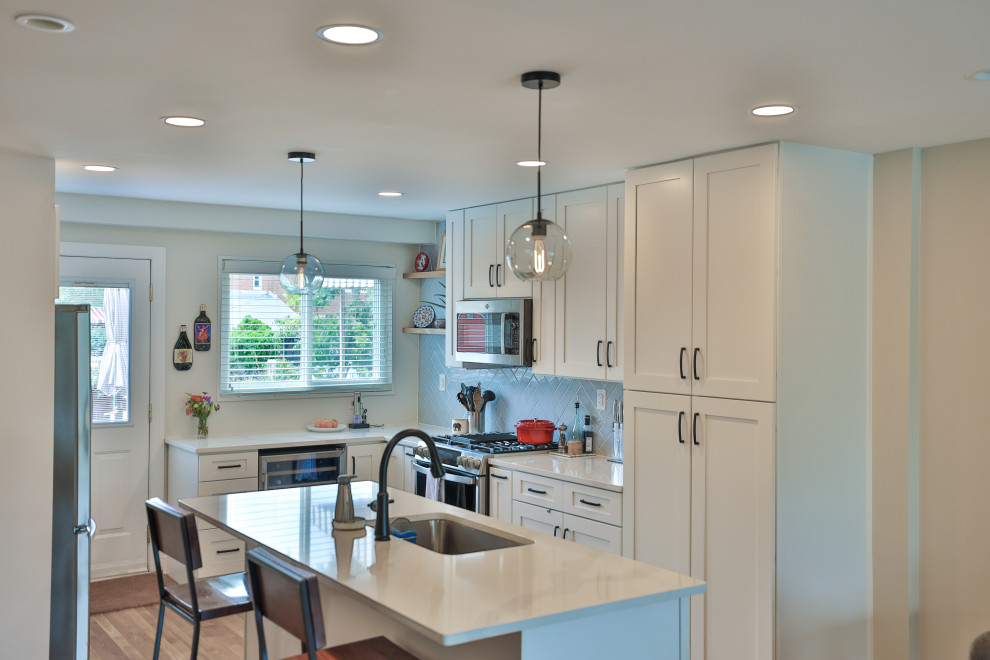 Foto de cocina minimalista de tamaño medio con despensa, puertas de armario blancas, electrodomésticos negros, suelo marrón y encimeras blancas